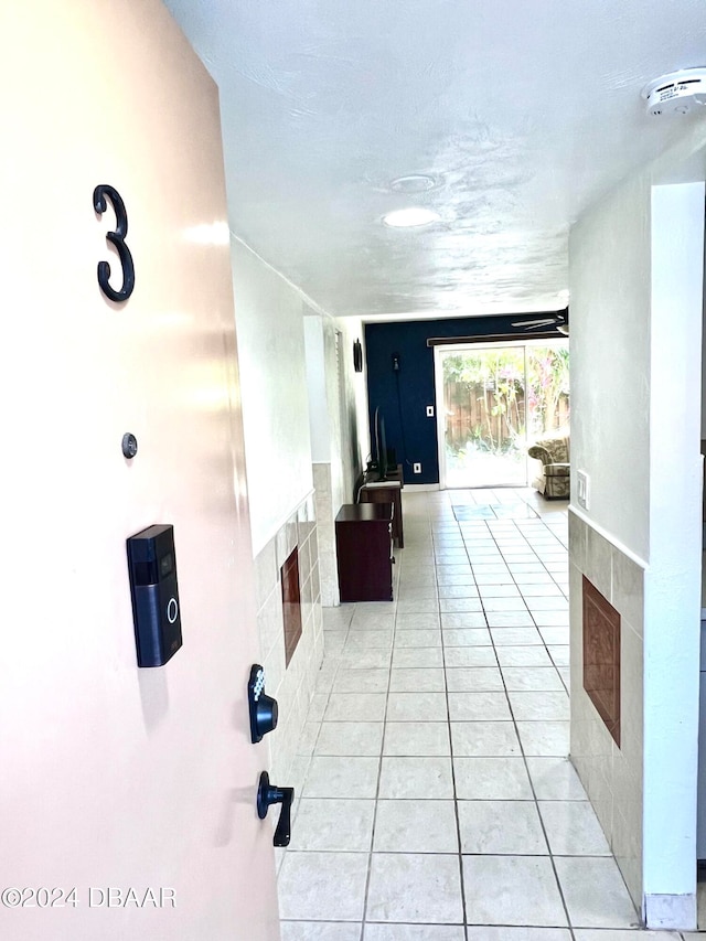 hall featuring tile walls and light tile patterned floors