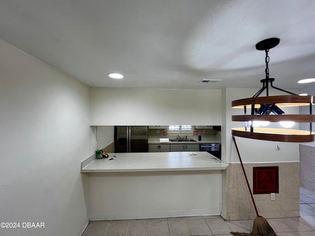 kitchen with tile walls, light tile patterned flooring, stainless steel fridge, and dishwasher