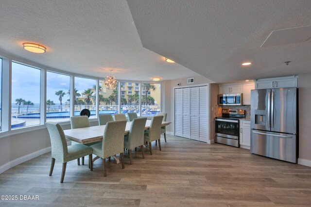2625 S Atlantic Ave Unit 10Nw, Daytona Beach Shores, FL 32118 - dining area featuring a textured ceiling, a chandelier, plenty of natural light, light wood-style flooring, and recessed lighting
