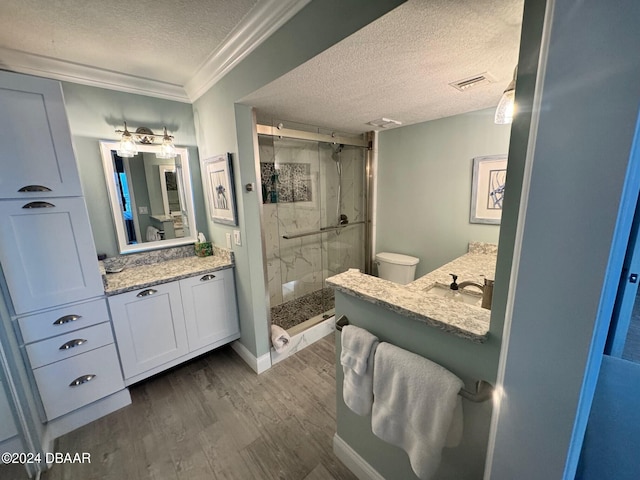 bathroom with vanity, a shower with door, ornamental molding, and a textured ceiling