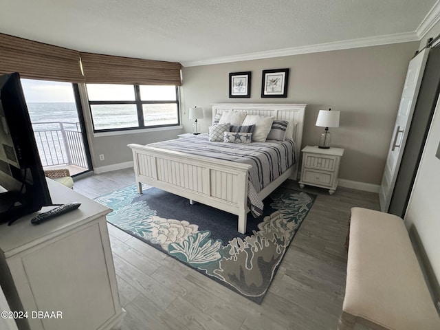 bedroom with access to exterior, a textured ceiling, hardwood / wood-style flooring, and crown molding