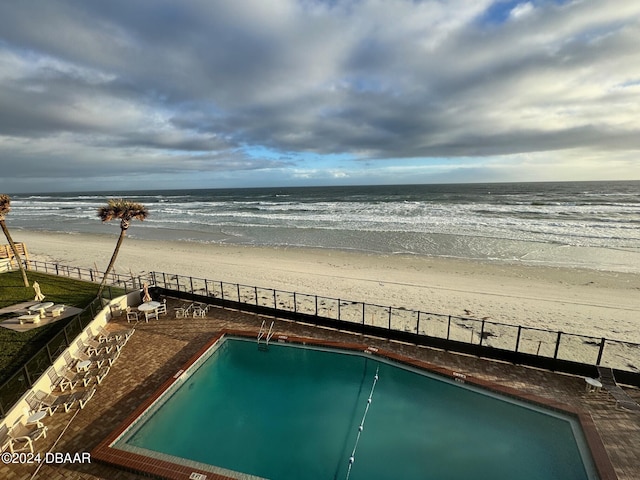 view of swimming pool featuring a water view and a beach view