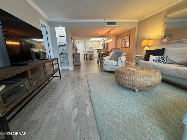 living room with a chandelier, hardwood / wood-style flooring, and ornamental molding