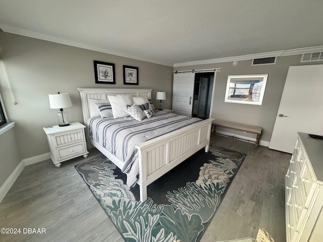 bedroom featuring a barn door, wood-type flooring, and crown molding