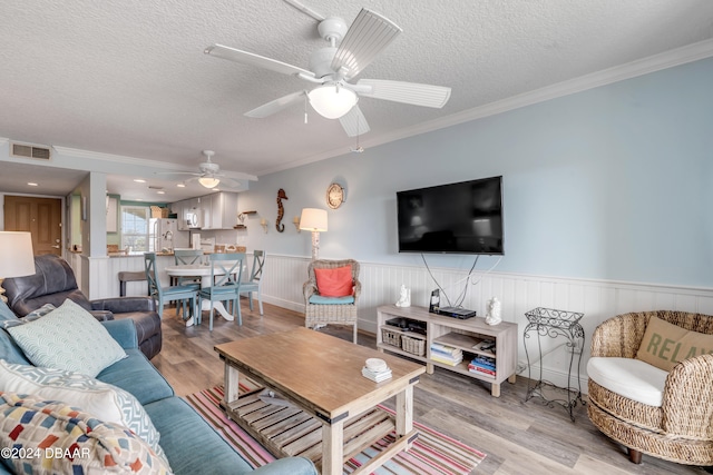 living room featuring a textured ceiling, light wood-type flooring, and crown molding