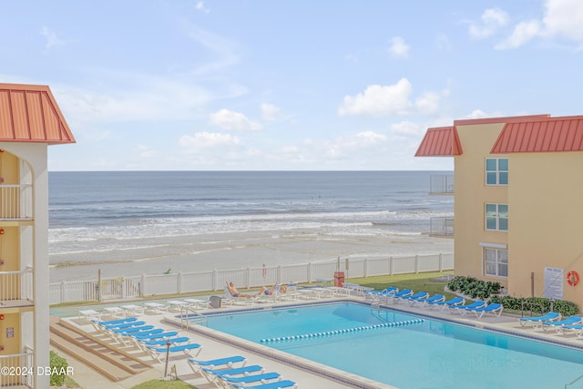 view of swimming pool featuring a water view and a beach view