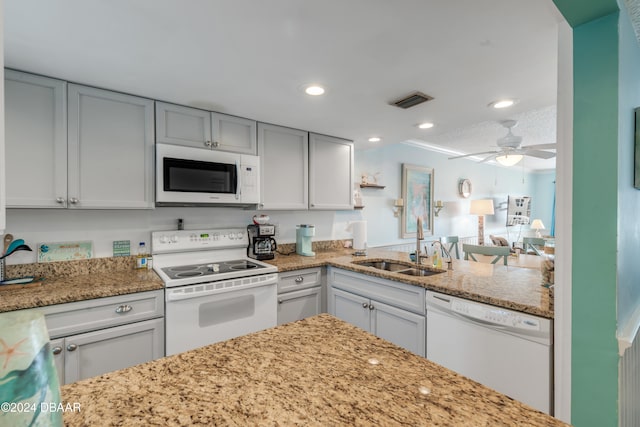 kitchen with light stone countertops, white appliances, ceiling fan, and sink