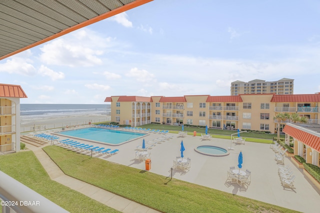 view of swimming pool with a community hot tub, a water view, a patio area, and a lawn