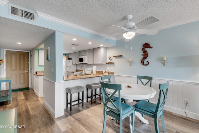 dining space with a textured ceiling, light hardwood / wood-style flooring, ceiling fan, and sink