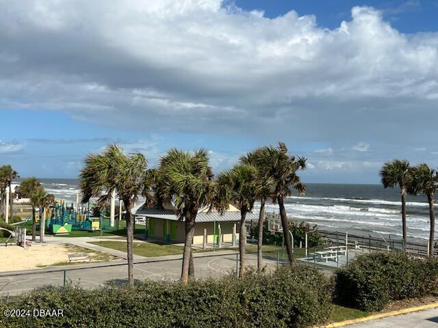 view of home's community with a playground, a water view, and a beach view