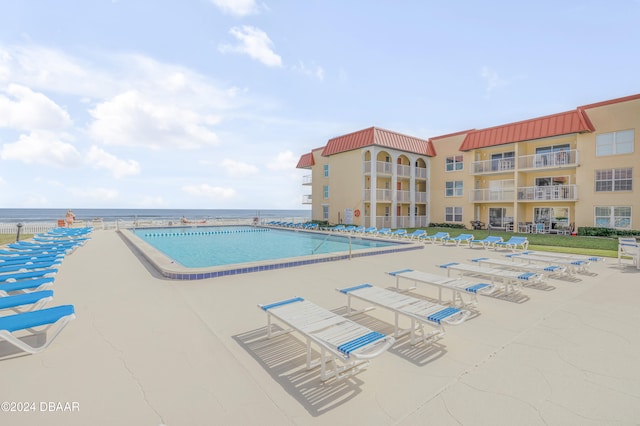 view of pool featuring a water view and a patio area