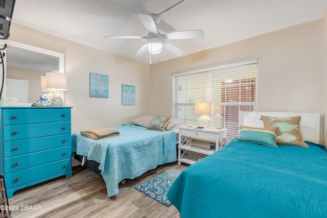 bedroom with a textured ceiling, light wood-type flooring, and ceiling fan