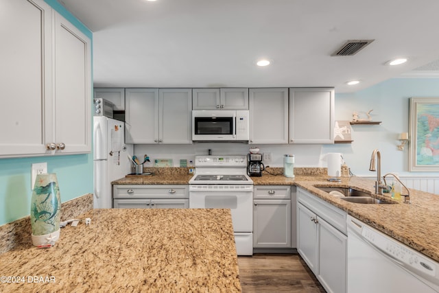 kitchen with light stone counters, wood-type flooring, white appliances, and sink