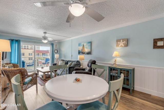 dining area with wood-type flooring, a textured ceiling, ceiling fan, and crown molding