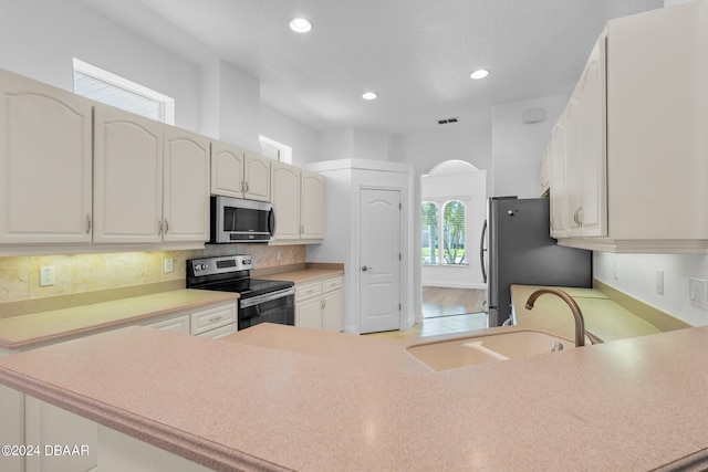 kitchen featuring kitchen peninsula, appliances with stainless steel finishes, a healthy amount of sunlight, and sink