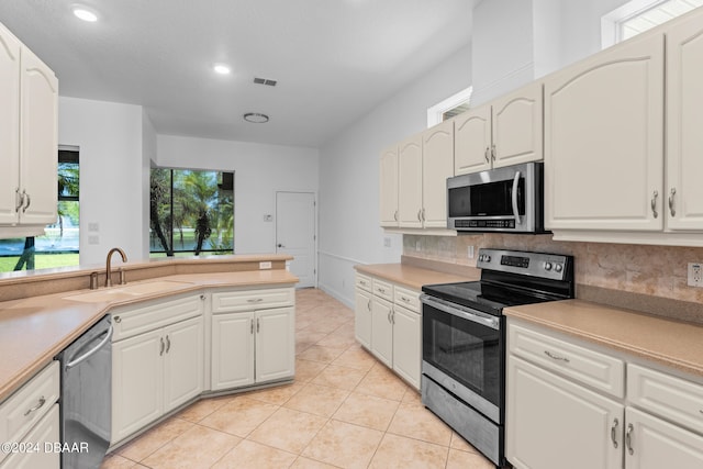 kitchen featuring stainless steel appliances, white cabinets, sink, and backsplash