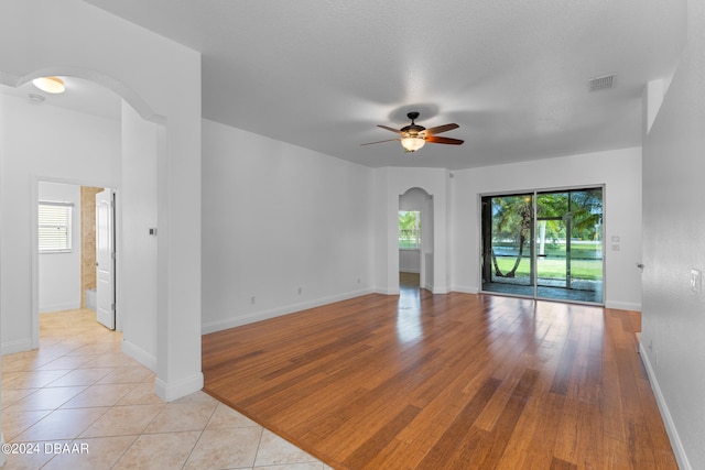 unfurnished room featuring light wood-type flooring, ceiling fan, and plenty of natural light