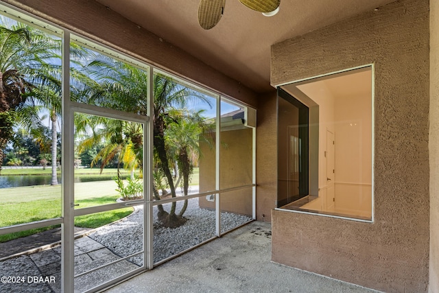 unfurnished sunroom with a wealth of natural light, a water view, and ceiling fan