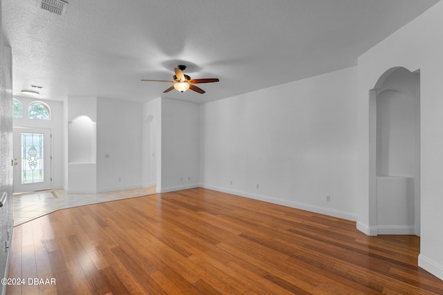 unfurnished living room with a textured ceiling, hardwood / wood-style flooring, and ceiling fan