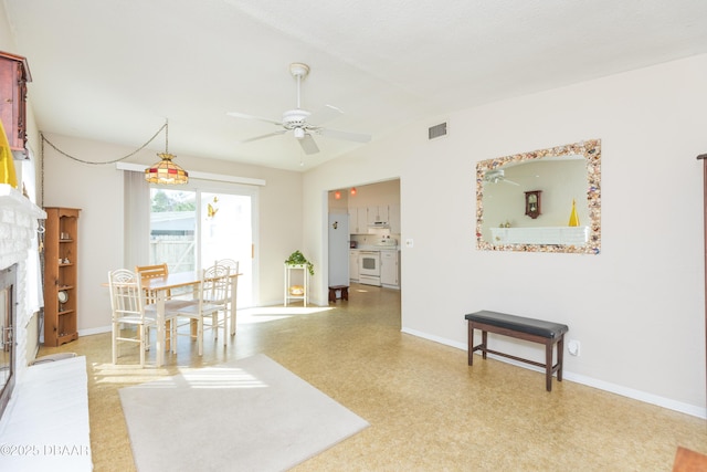 dining room with lofted ceiling, a stone fireplace, and ceiling fan