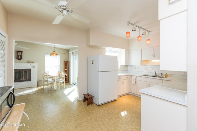 kitchen featuring sink, white cabinetry, decorative backsplash, decorative light fixtures, and white fridge