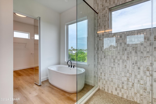 bathroom featuring a wealth of natural light, plus walk in shower, and hardwood / wood-style flooring