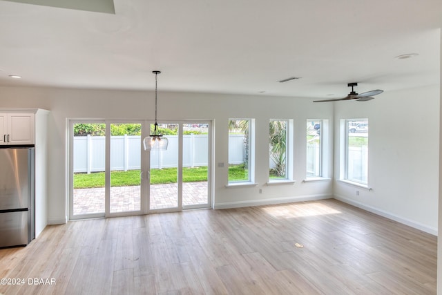 unfurnished living room featuring light hardwood / wood-style flooring and ceiling fan with notable chandelier