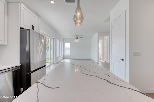 kitchen featuring pendant lighting, ceiling fan, light stone countertops, white cabinetry, and stainless steel appliances