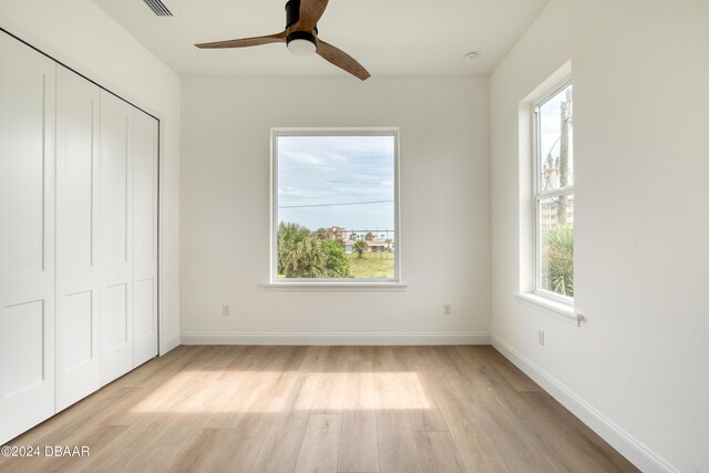 unfurnished bedroom featuring a closet, light hardwood / wood-style floors, and ceiling fan