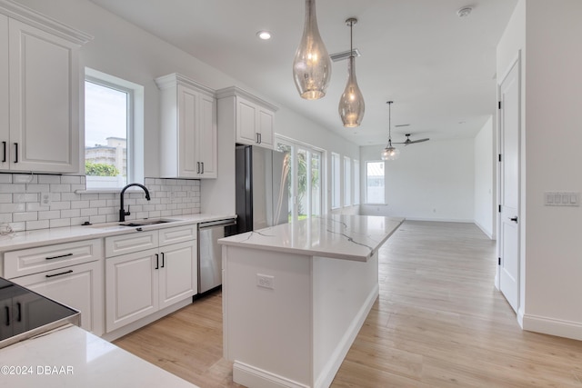 kitchen with white cabinets, a kitchen island, stainless steel appliances, and decorative light fixtures