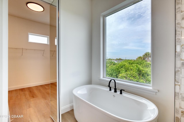 bathroom featuring wood-type flooring, plenty of natural light, and a bathing tub