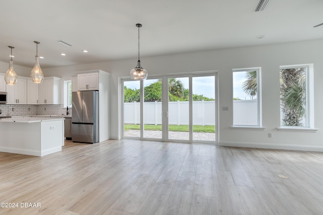 kitchen featuring white cabinets, a healthy amount of sunlight, appliances with stainless steel finishes, and pendant lighting