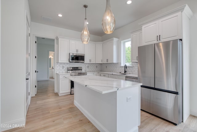 kitchen featuring white cabinets, appliances with stainless steel finishes, light hardwood / wood-style flooring, and a kitchen island