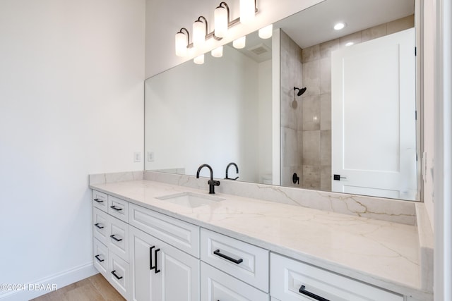 bathroom featuring wood-type flooring, vanity, and a tile shower