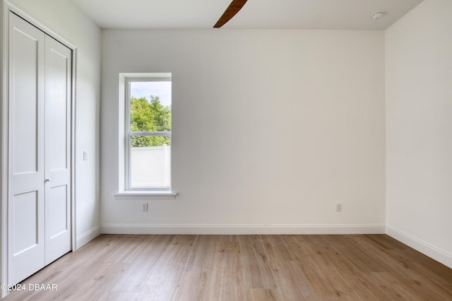 unfurnished bedroom featuring ceiling fan, a closet, and light wood-type flooring