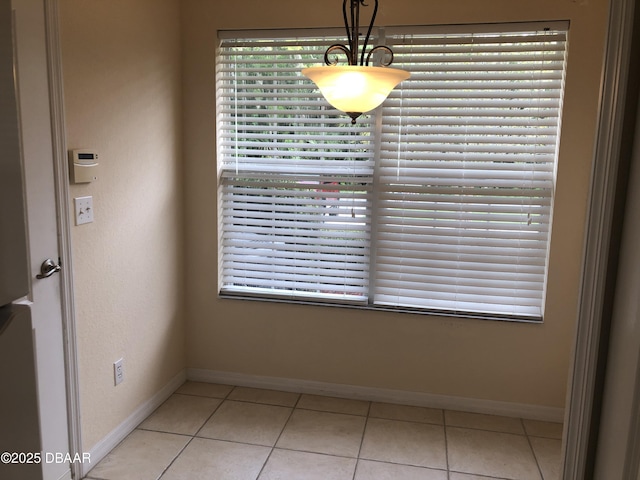 unfurnished dining area with light tile patterned flooring and baseboards