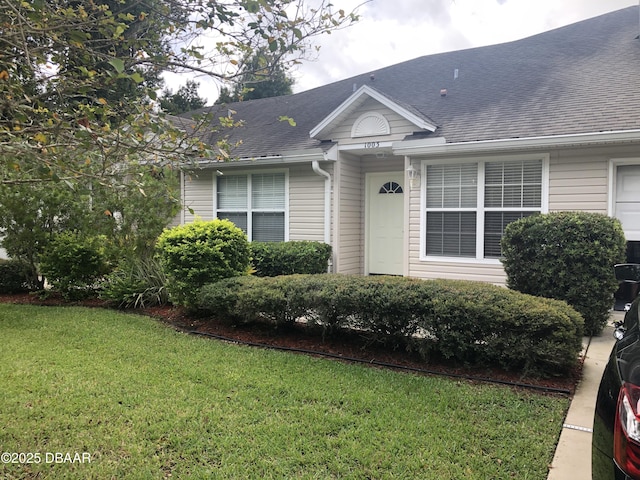 view of front facade with roof with shingles and a front yard