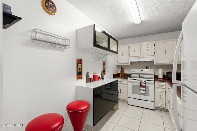 2711 N Halifax Ave Unit 372, Daytona Beach, FL 32118 - kitchen featuring white appliances, under cabinet range hood, light tile patterned floors, a textured ceiling, and white cabinets