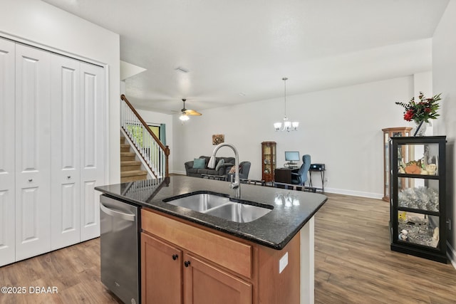 kitchen with dishwasher, wood finished floors, a center island with sink, and a sink