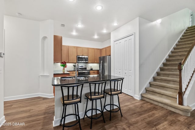 kitchen featuring a sink, stainless steel appliances, dark countertops, and dark wood-style flooring