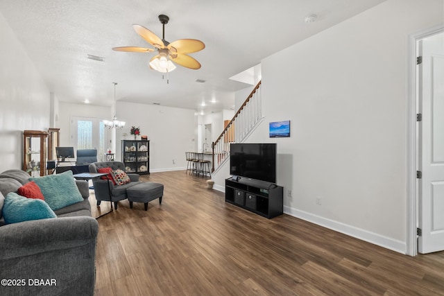 living area with visible vents, baseboards, stairway, ceiling fan with notable chandelier, and wood finished floors