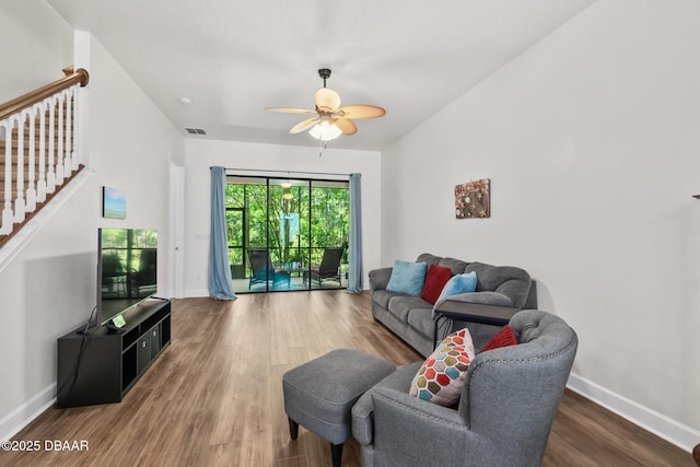 living room with stairway, wood finished floors, visible vents, baseboards, and ceiling fan