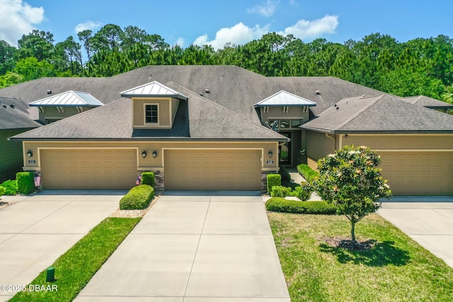 view of front of house with driveway, roof with shingles, a standing seam roof, a front lawn, and metal roof