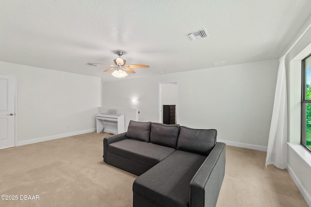 living area featuring visible vents, light colored carpet, a textured ceiling, and baseboards