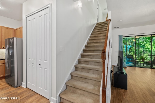 stairs featuring visible vents, baseboards, and wood finished floors