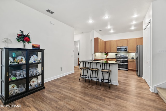 kitchen with a sink, a peninsula, wood finished floors, and stainless steel appliances