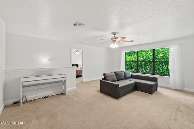 carpeted living area with visible vents, baseboards, a textured ceiling, and ceiling fan