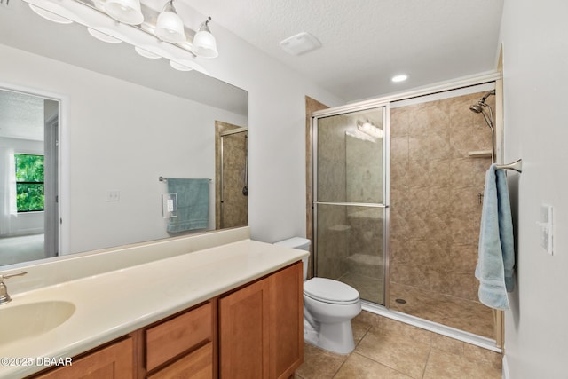 bathroom with vanity, a shower stall, a textured ceiling, tile patterned floors, and toilet