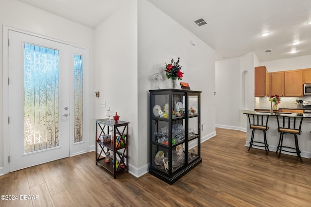 foyer entrance featuring visible vents, arched walkways, baseboards, and dark wood-style floors