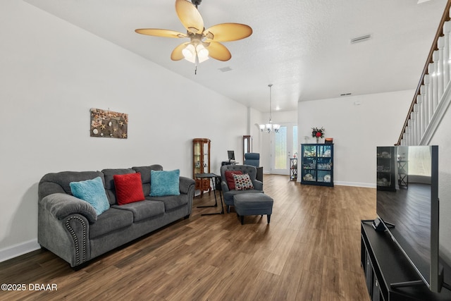 living room featuring visible vents, ceiling fan with notable chandelier, wood finished floors, baseboards, and stairs